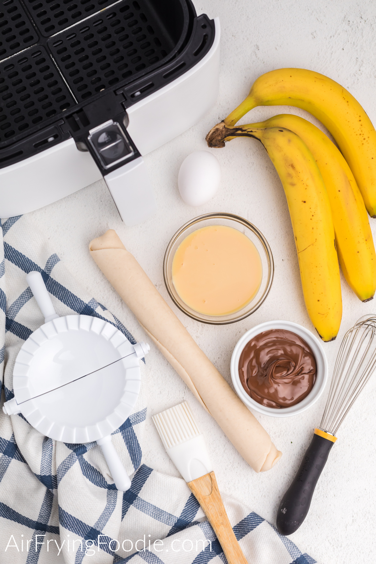 Table with ingredients and items needed to make banana nutella hand pies in the air fryer.