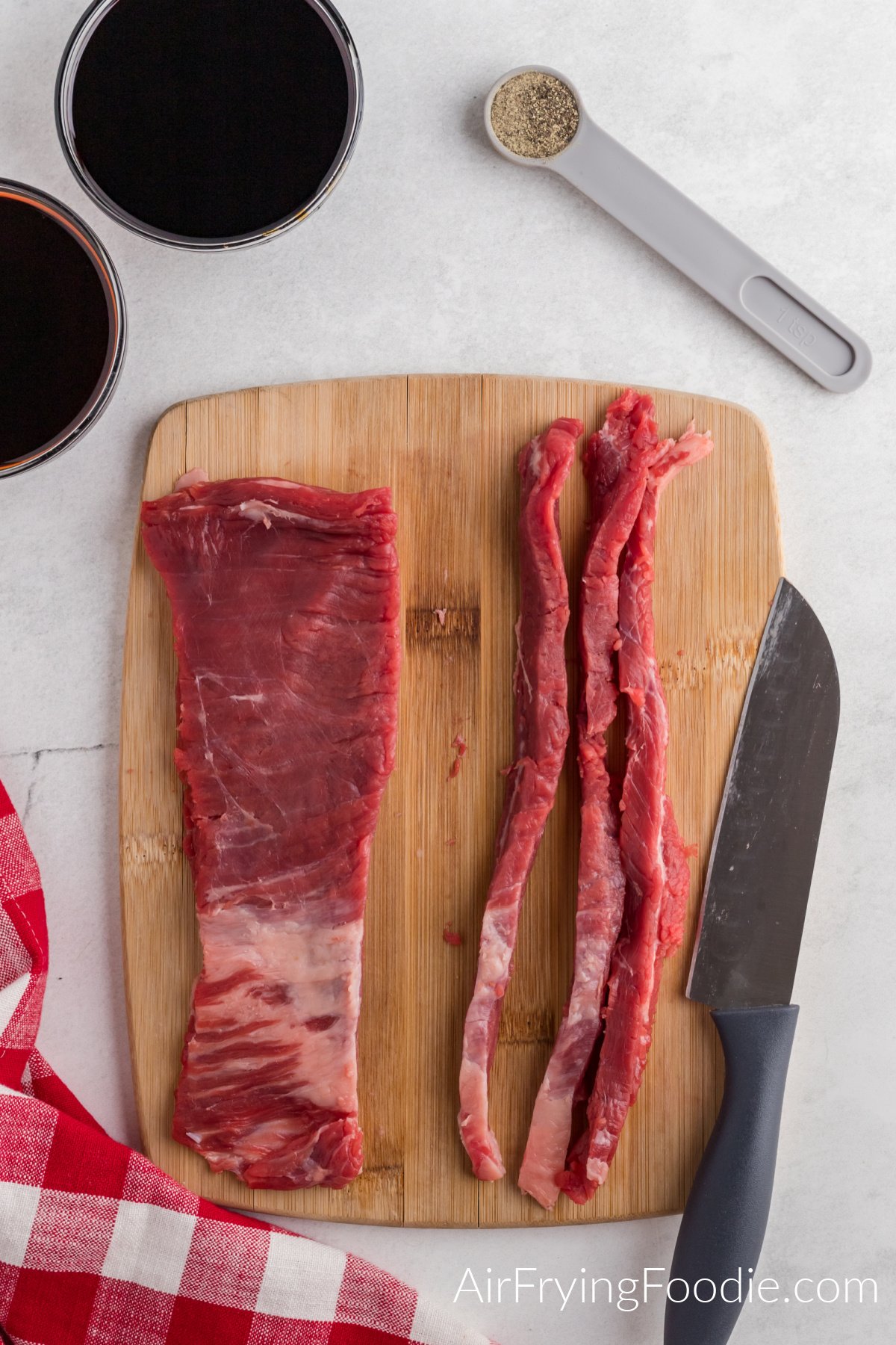 Flank steak cut into strips on a cutting board.