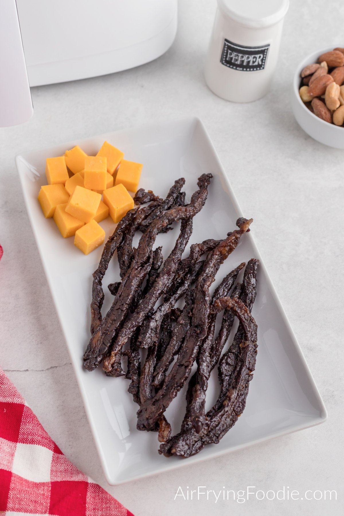 Strips of air fryer beef jerky on a plate with cheese. Ready to eat.