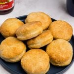 Golden fluffy air fryer biscuits stacked on a blue plate.