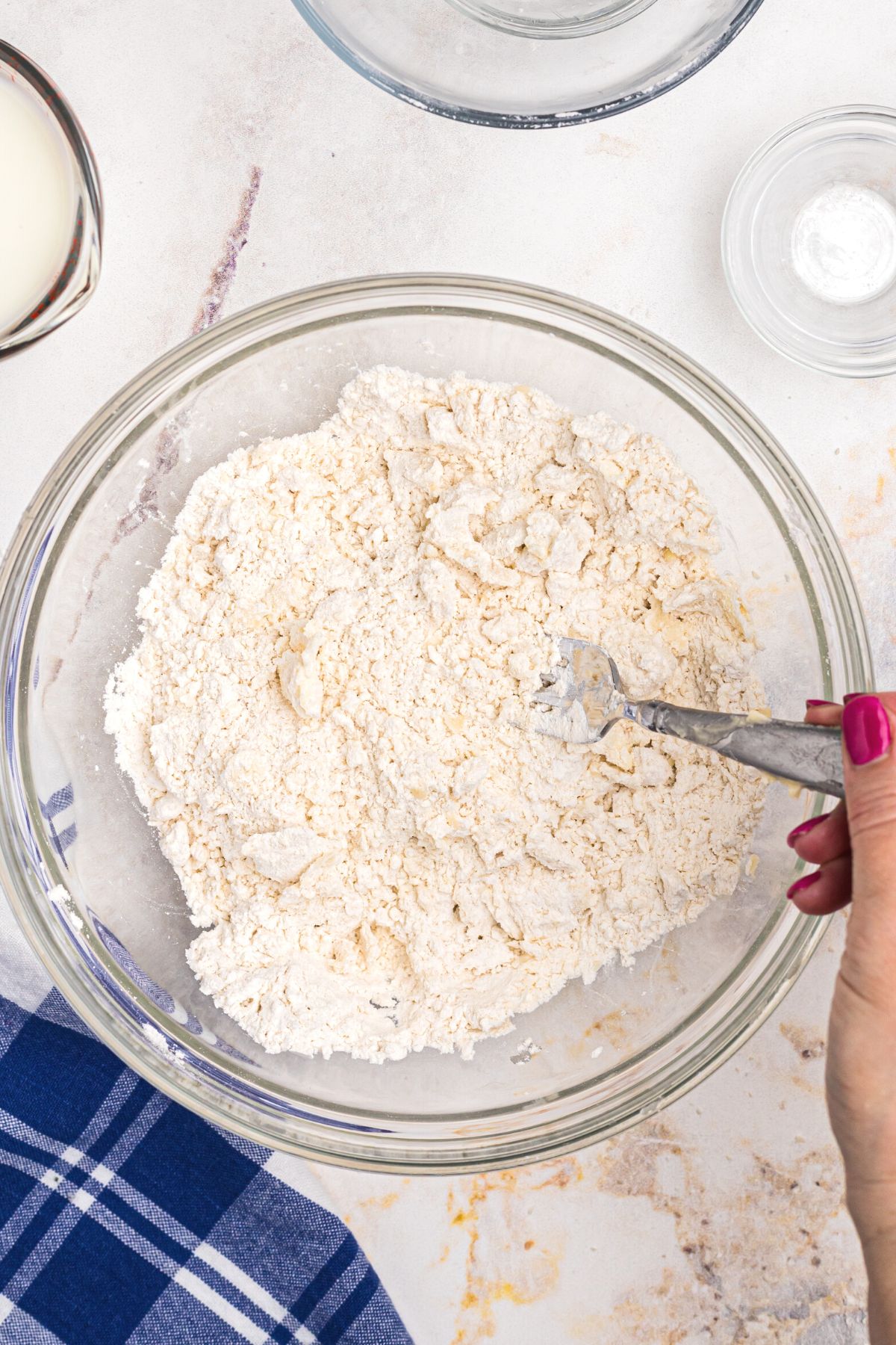 Flour and other dry ingredients mixed with butter in a clear glass bowl.