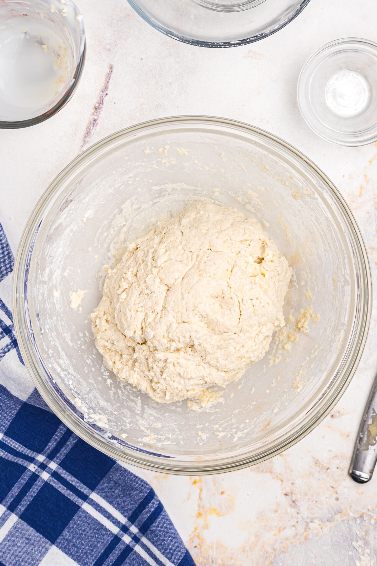 Dough ingredients mixed in a clear glass bowl until a soft ball of dough forms.