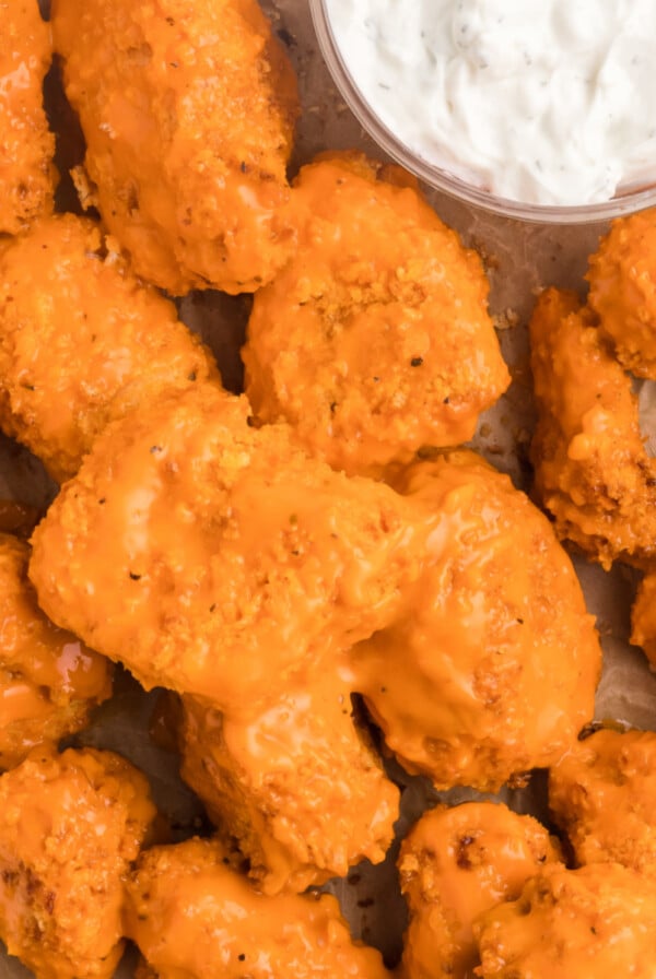 Boneless wings made in the air fryer, topped with sauce, and served with dipping sauce on a tray.