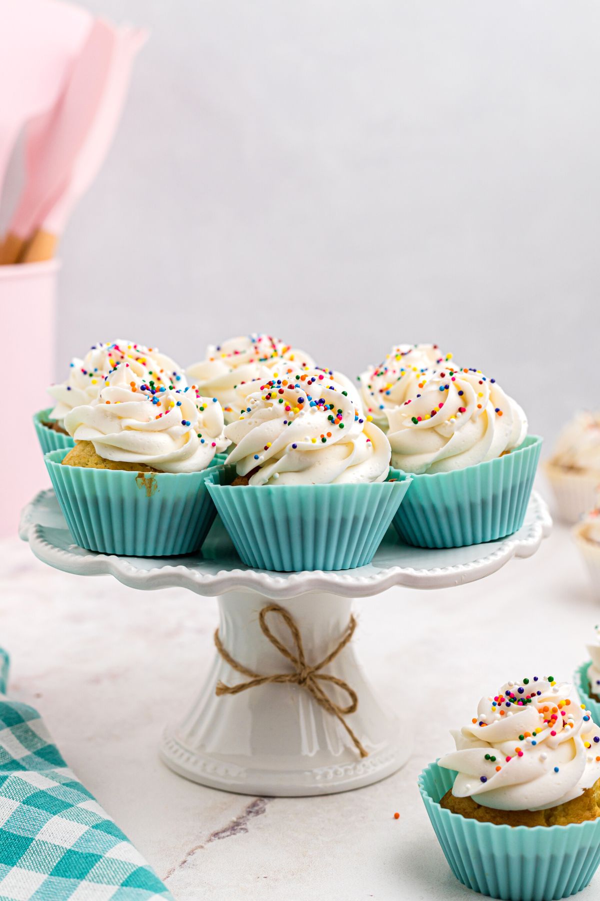 Air fried cupcakes in light blue liners on a white marble cake plate