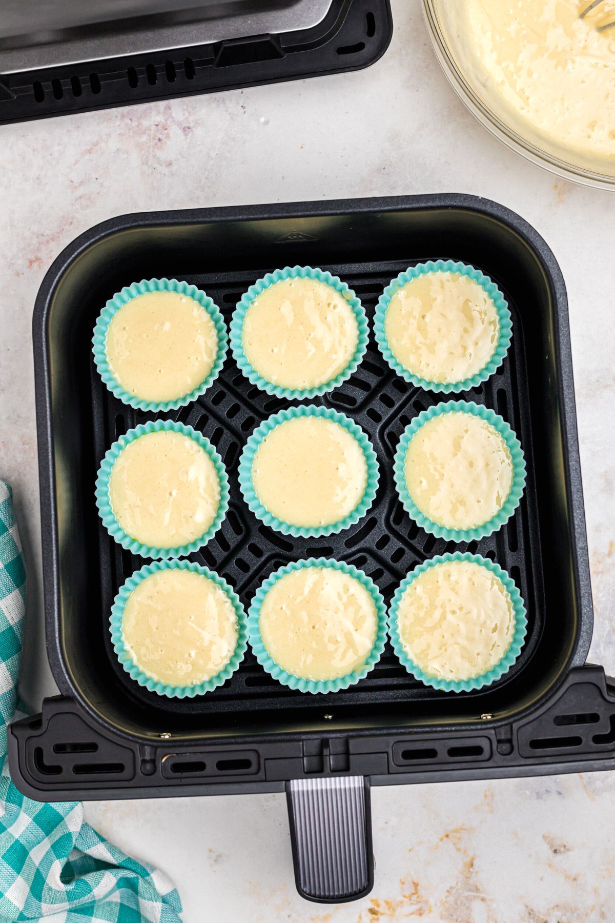Silicone muffin liners filled with cake batter in the air fryer basket