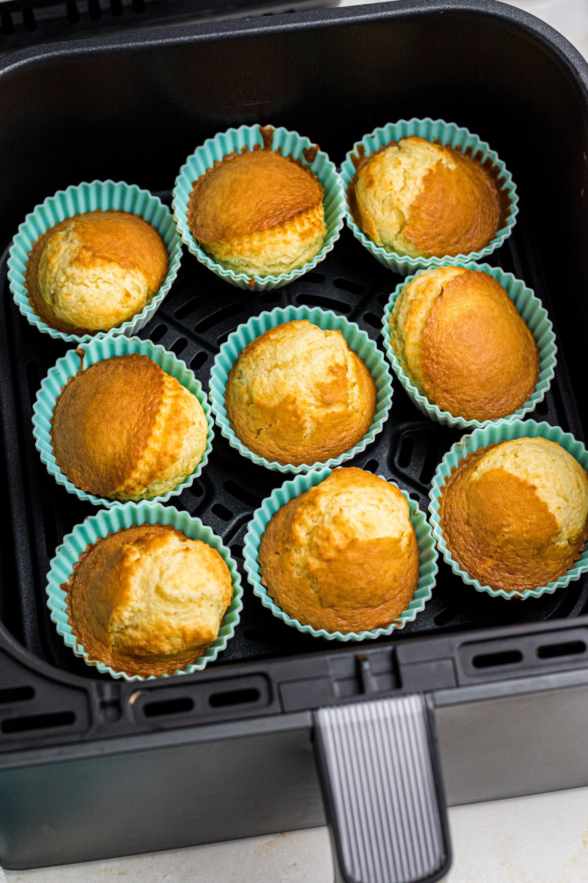 Golden French vanilla cupcakes in silicone liners in the air fryer basket.