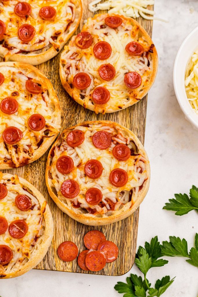Golden Crispy English Muffin Pizzas on a wooden cutting board. 