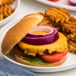 Air fryer frozen burger made with cheese and topped with onion, tomato, and lettuce.