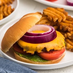 Air fryer frozen burger made with cheese and topped with onion, tomato, and lettuce.