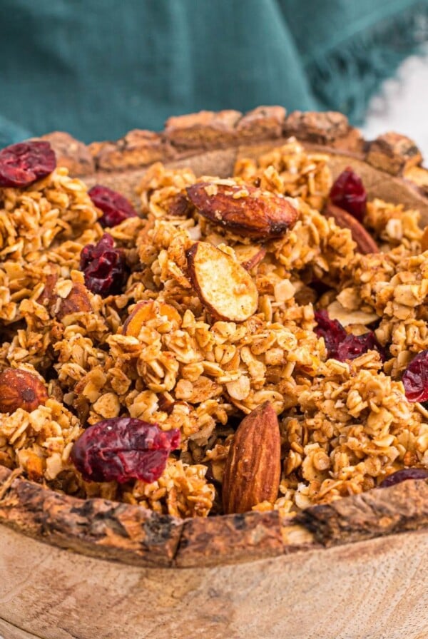 Golden granola in a wooden bowl filled with nuts and dried fruit.