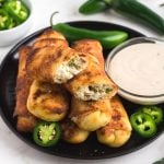 Golden crispy cream cheese egg rolls on a black plate