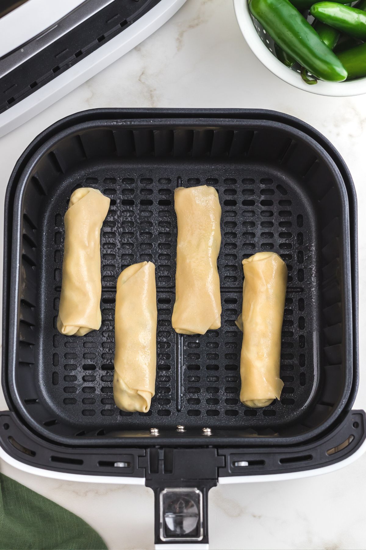 Rolled and filled wonton wrappers in the air fryer basket before being cooked