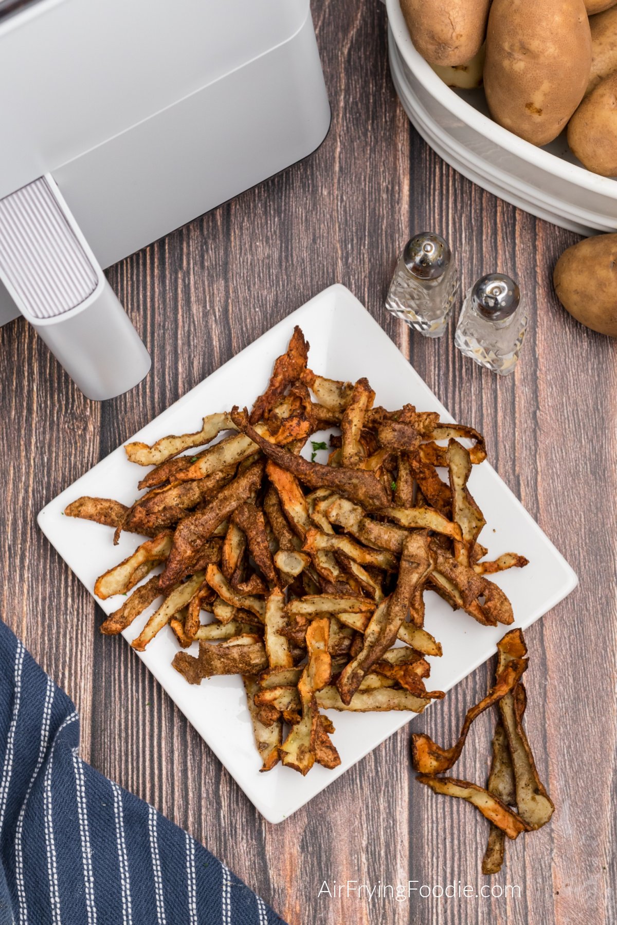 Overhead photo of seasoned potato peelings made in the air fryer and served on a white plate.