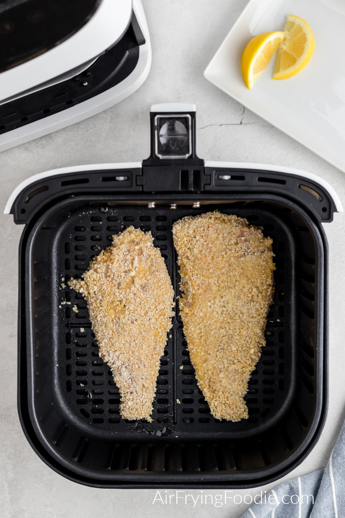 Breaded fish in air fryer basket, ready to cook.