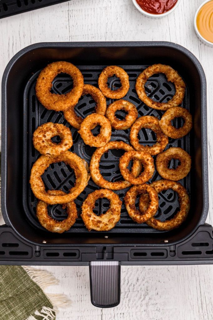 Golden crispy cooked onion rings in the air fryer basket.