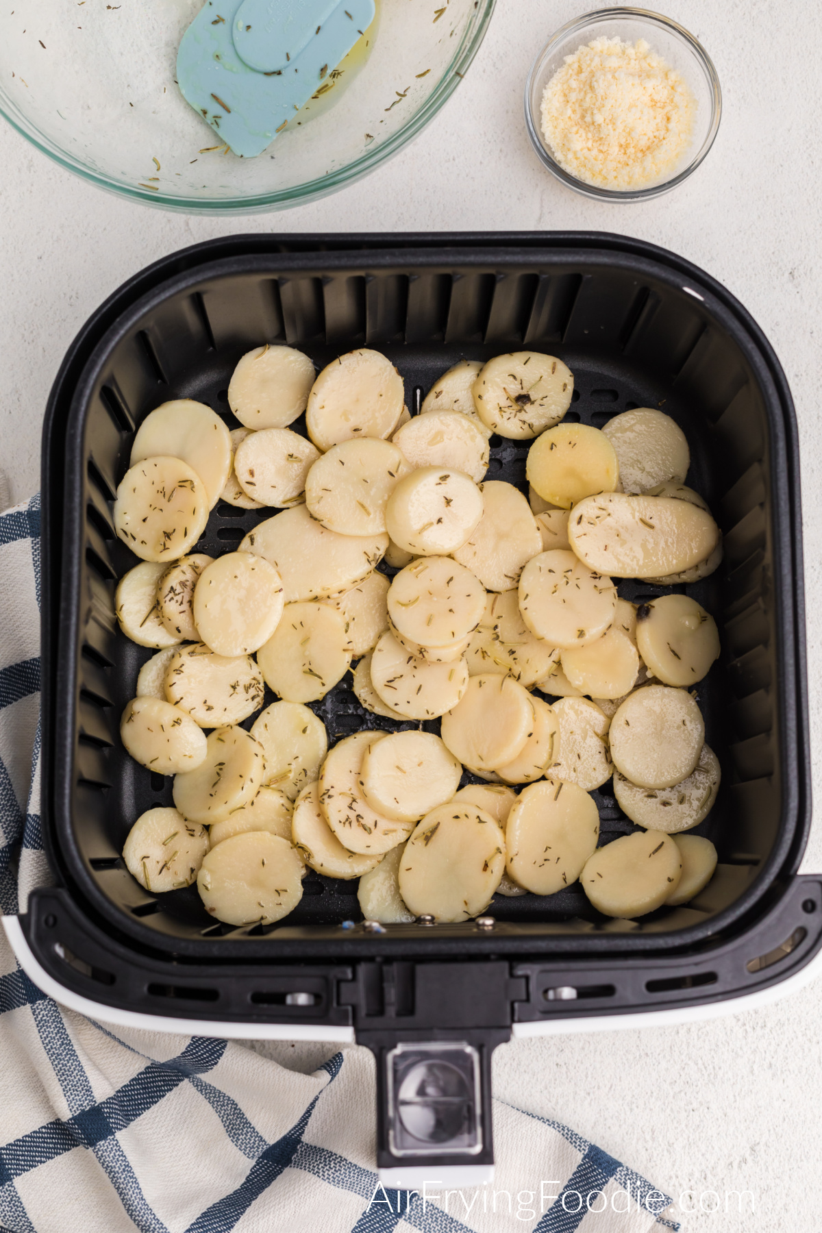 Sliced potatoes in air fryer basket, ready to be cooked.
