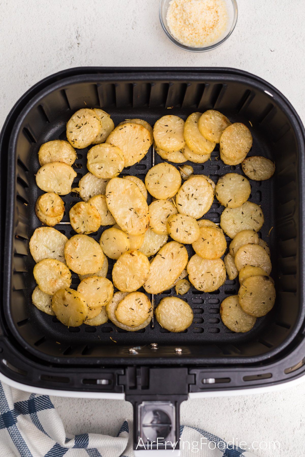 Air fried sliced potatoes in the basket of the air fryer.