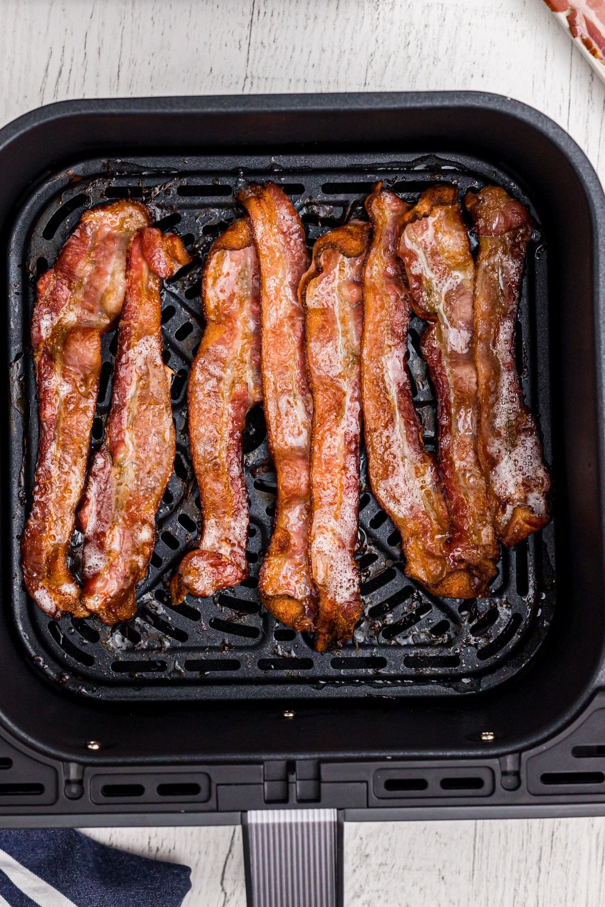Juicy crispy bacon in the air fryer basket.