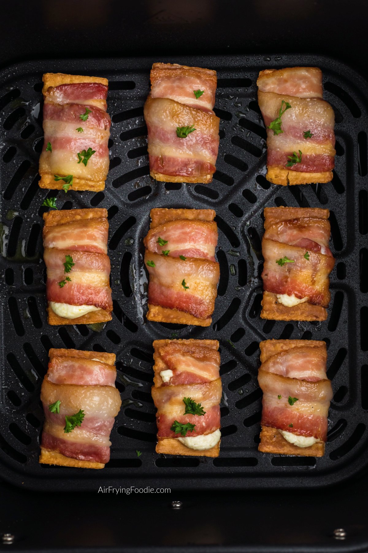 Close up photo of air fried bacon wrapped cream cheese crackers in the basket of the air fryer.