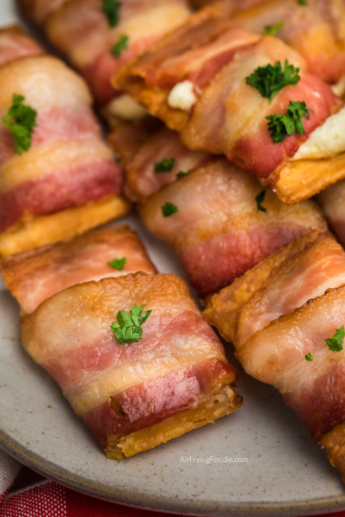 Bacon wrapped cream cheese crackers on a plate, ready to eat.