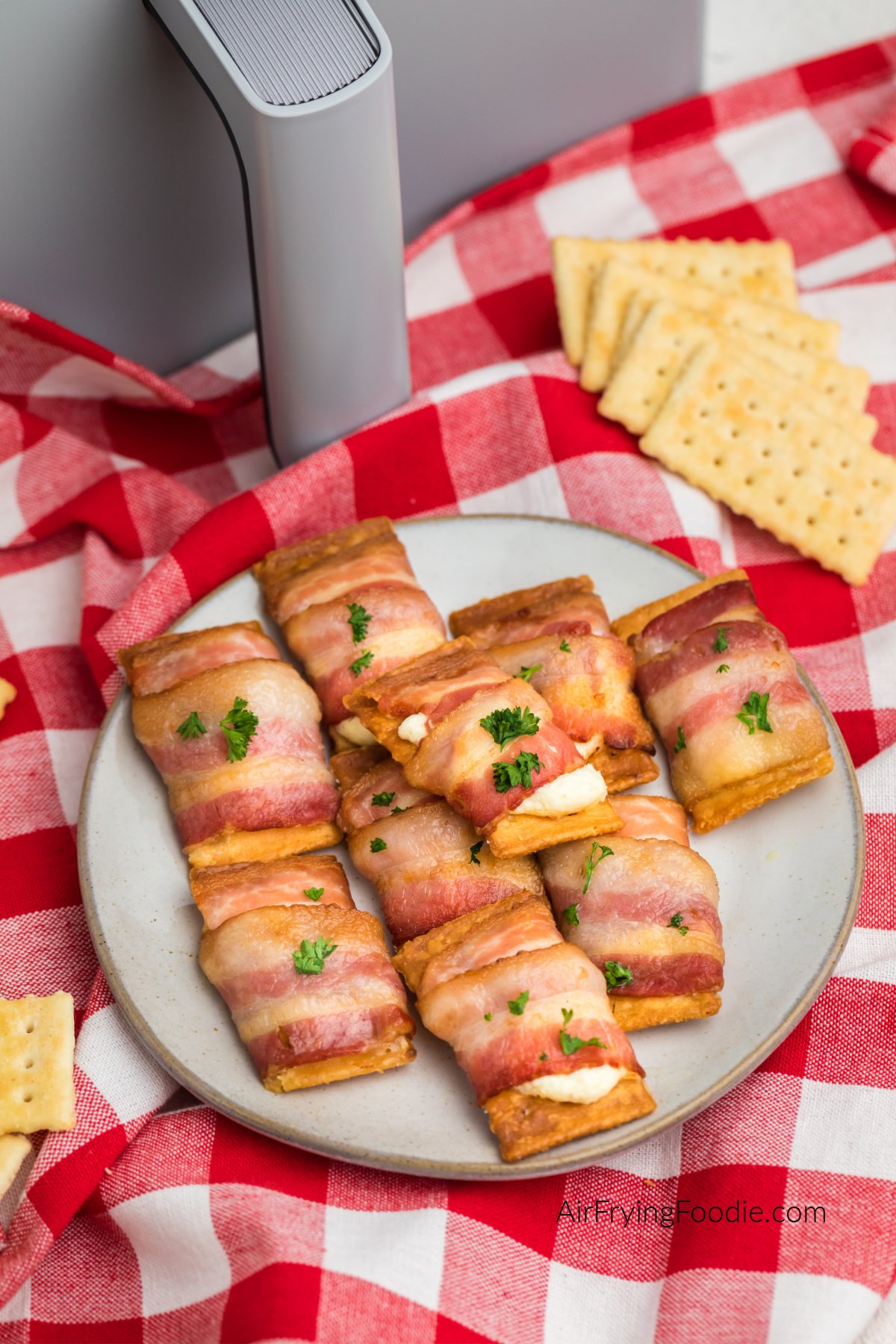 Air fried bacon wrapped cream cheese crackers on a plate ready to serve.
