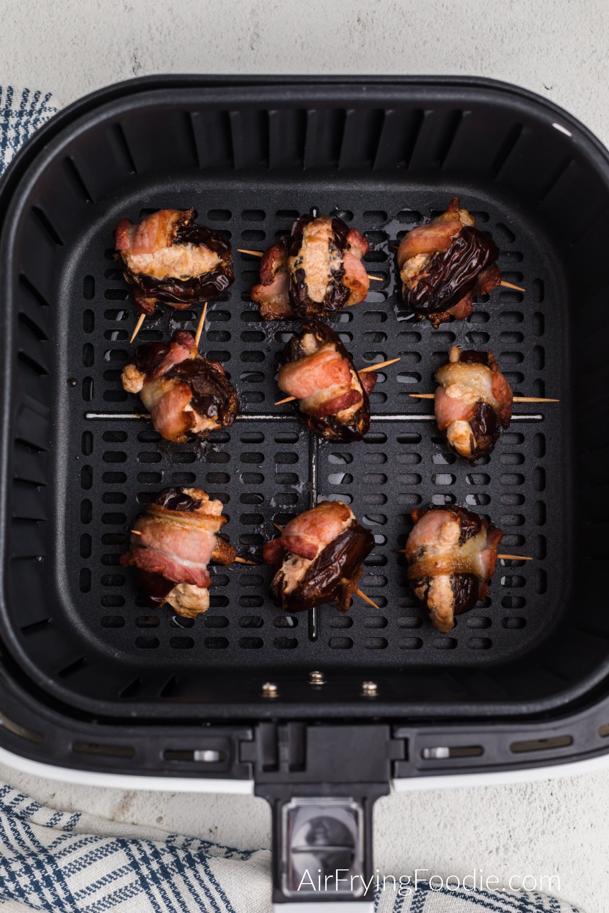 Air fried bacon wrapped dates in the basket of the air fryer.