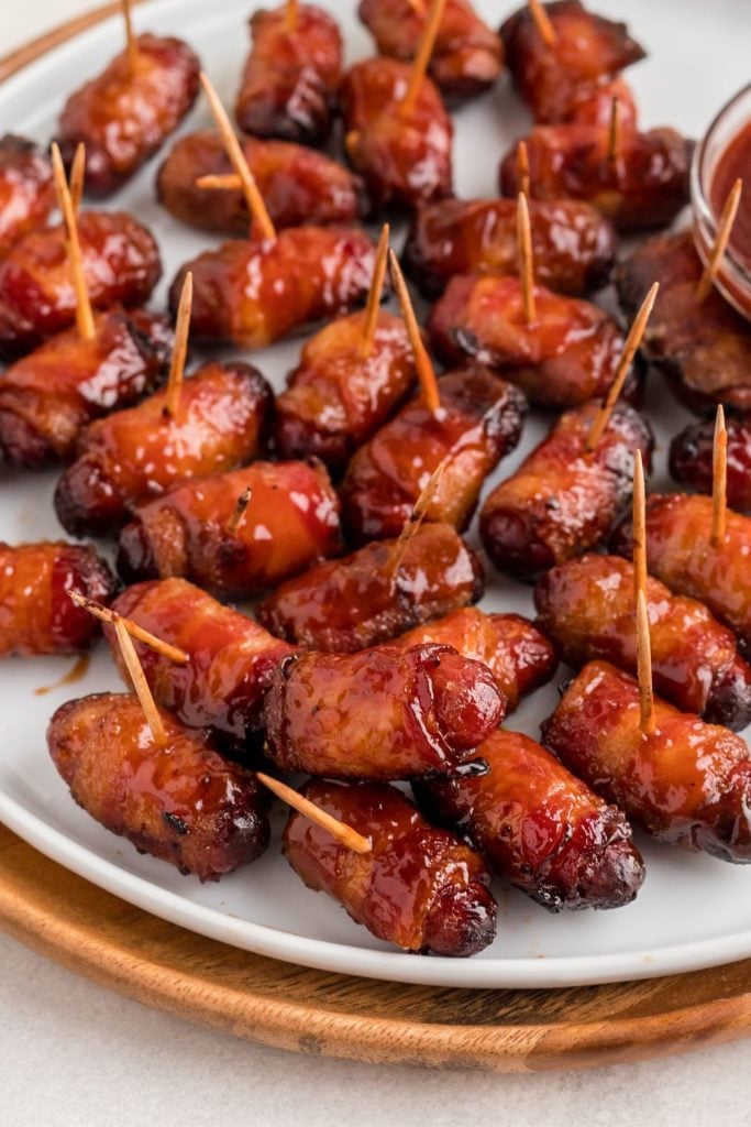 Juicy BBQ coated bacon wrapped smokies on a white plate.