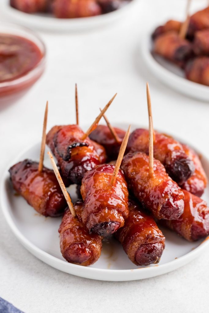 BBQ glazed bacon wrapped smokies on a small white plate