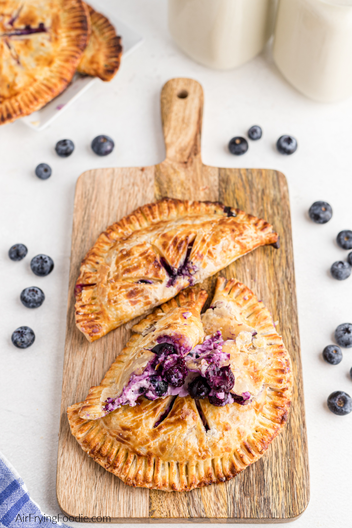 Air fried hand pies stuffed with blueberries and cream cheese, served on a cutting board. 
