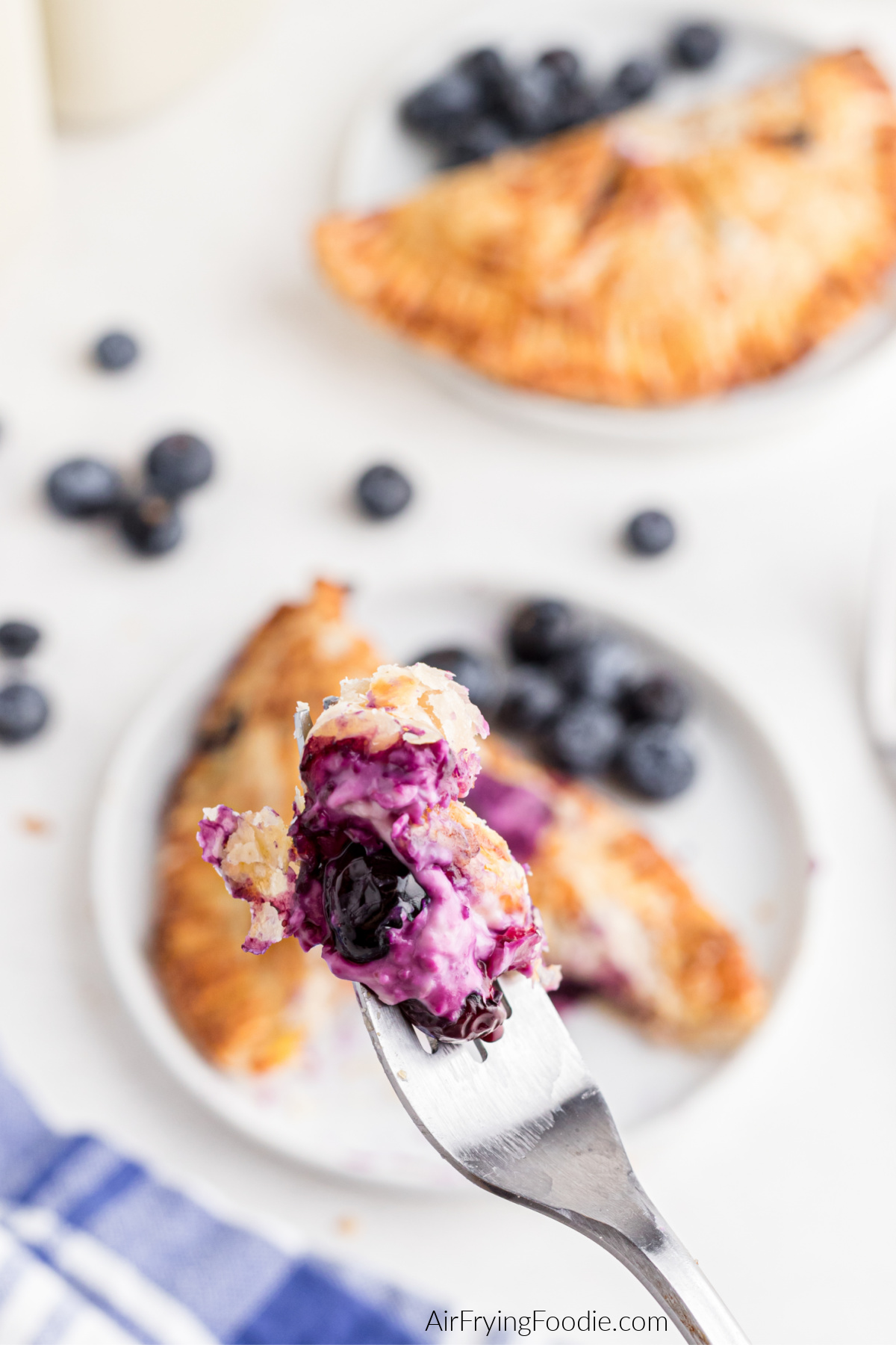 Bite of blueberry hand pie on the end of a fork. 