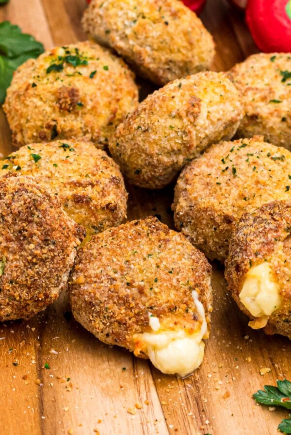 Breaded fried cheese rounds on a wooden cutting board.