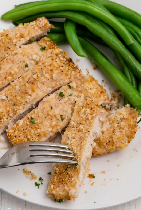 Overhead sliced air fried chicken breast with side of green beans on a white plate.