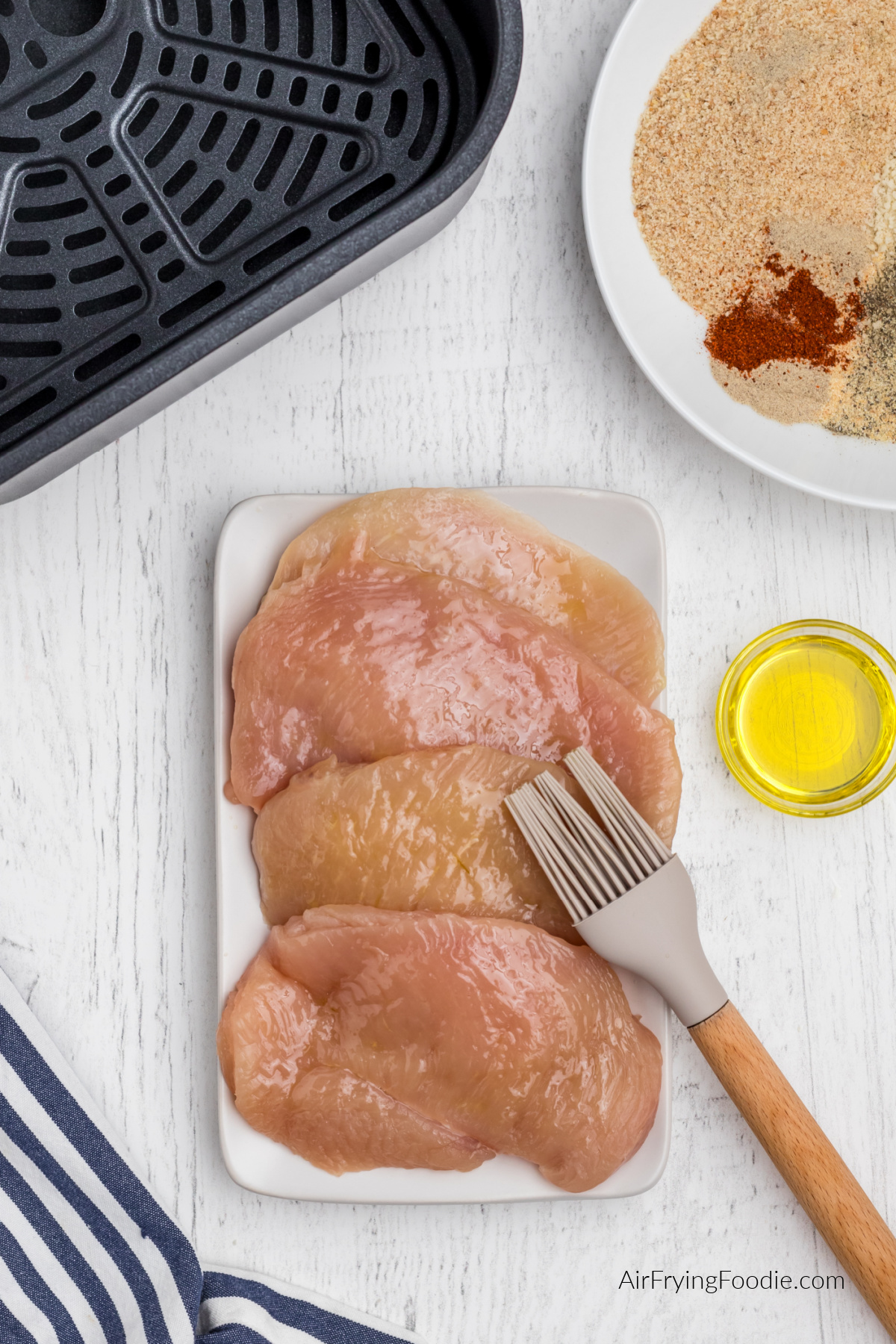 Chicken breast being brushed with olive oil.