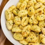Golden crispy gnocchi in a white bowl, seasoned.