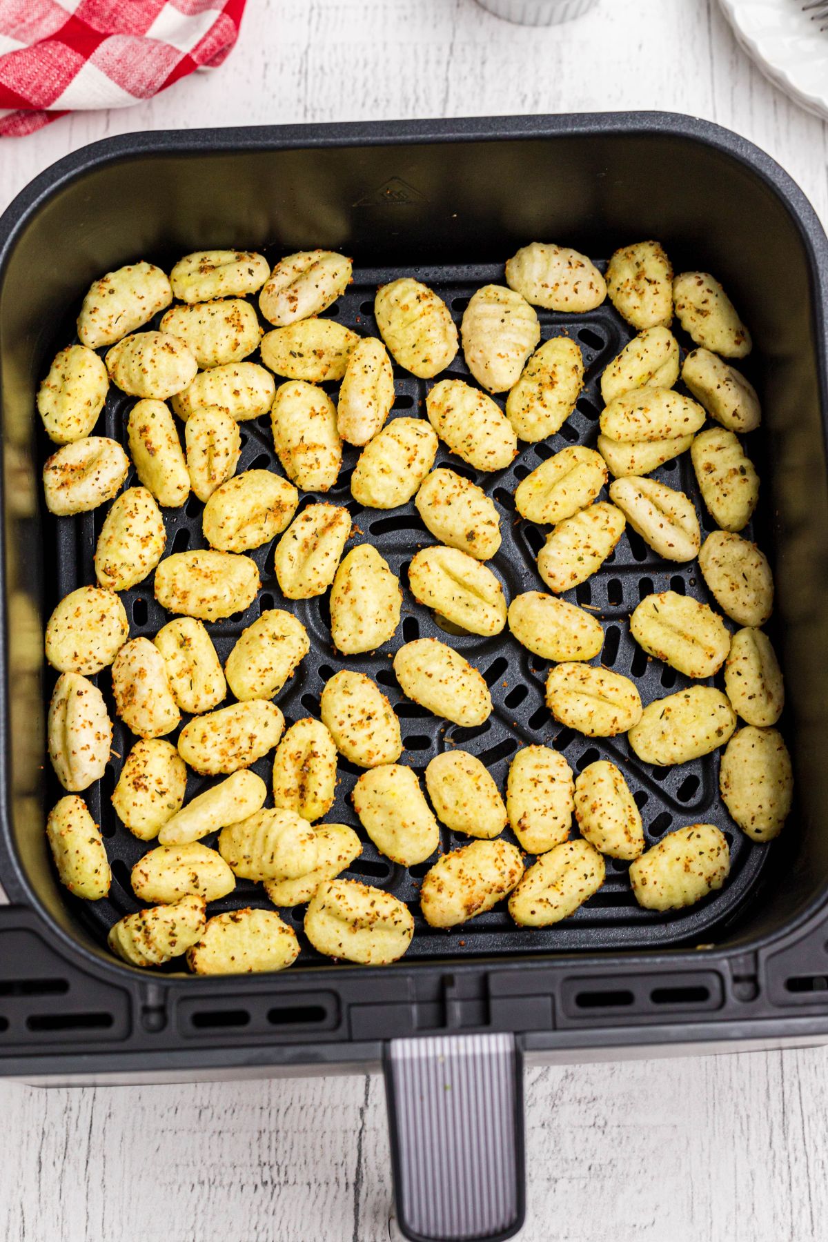 Golden crispy seasoned gnocci in the air fryer basket after air frying.