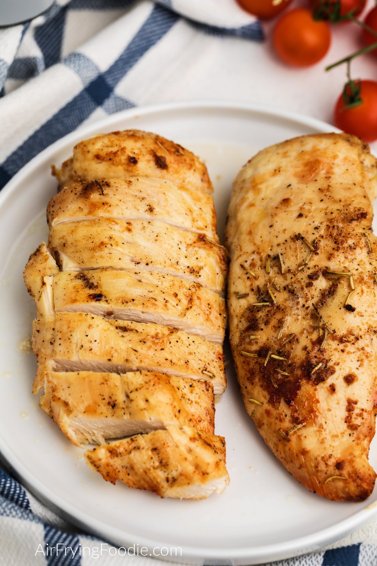 Air fryer grilled chicken breast on a white plate, sliced and whole chicken breasts on the plate.