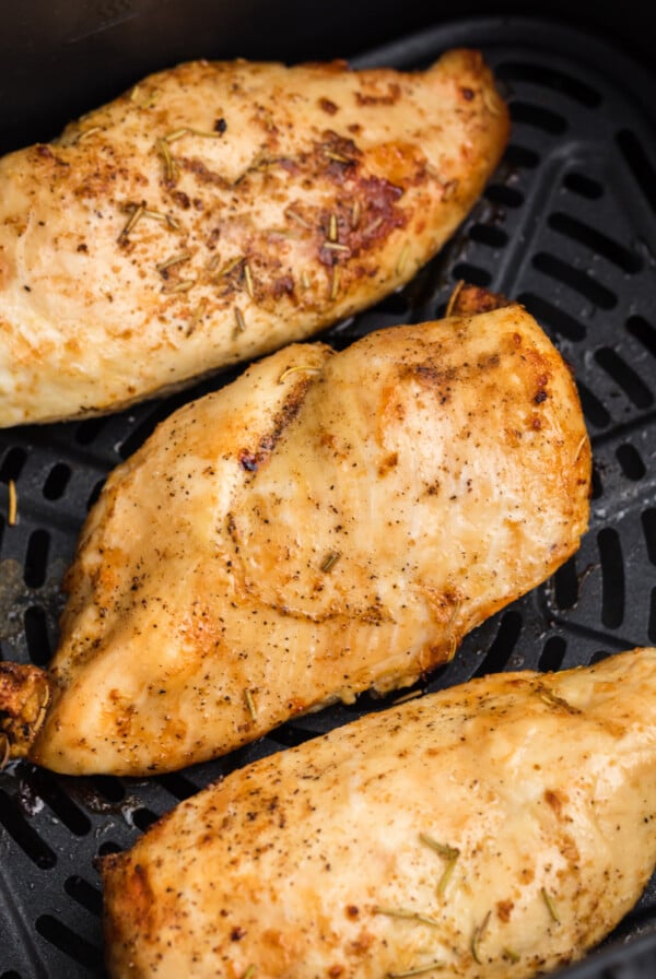 Overhead shot of grilled chicken breast in the basket of the air fryer.