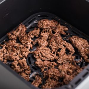 Crumbled ground beef in the basket of the air fryer, ready to serve.