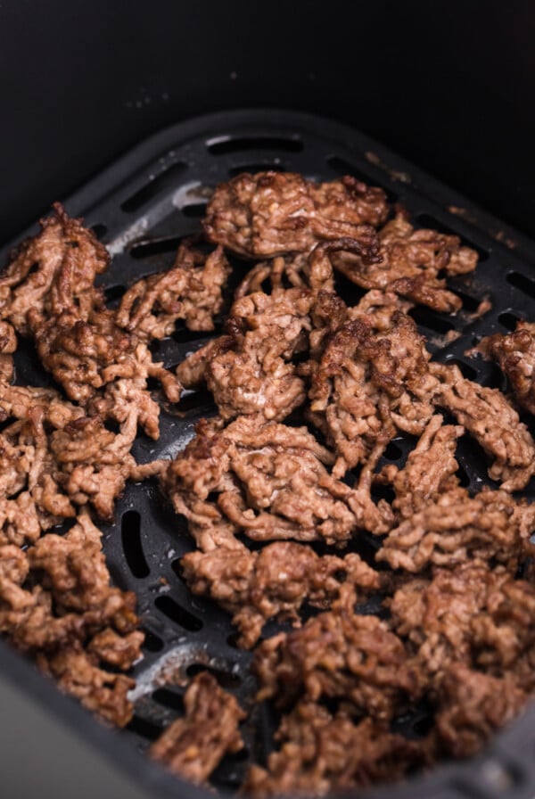 Crumbled ground beef in the basket of the air fryer, ready to serve.