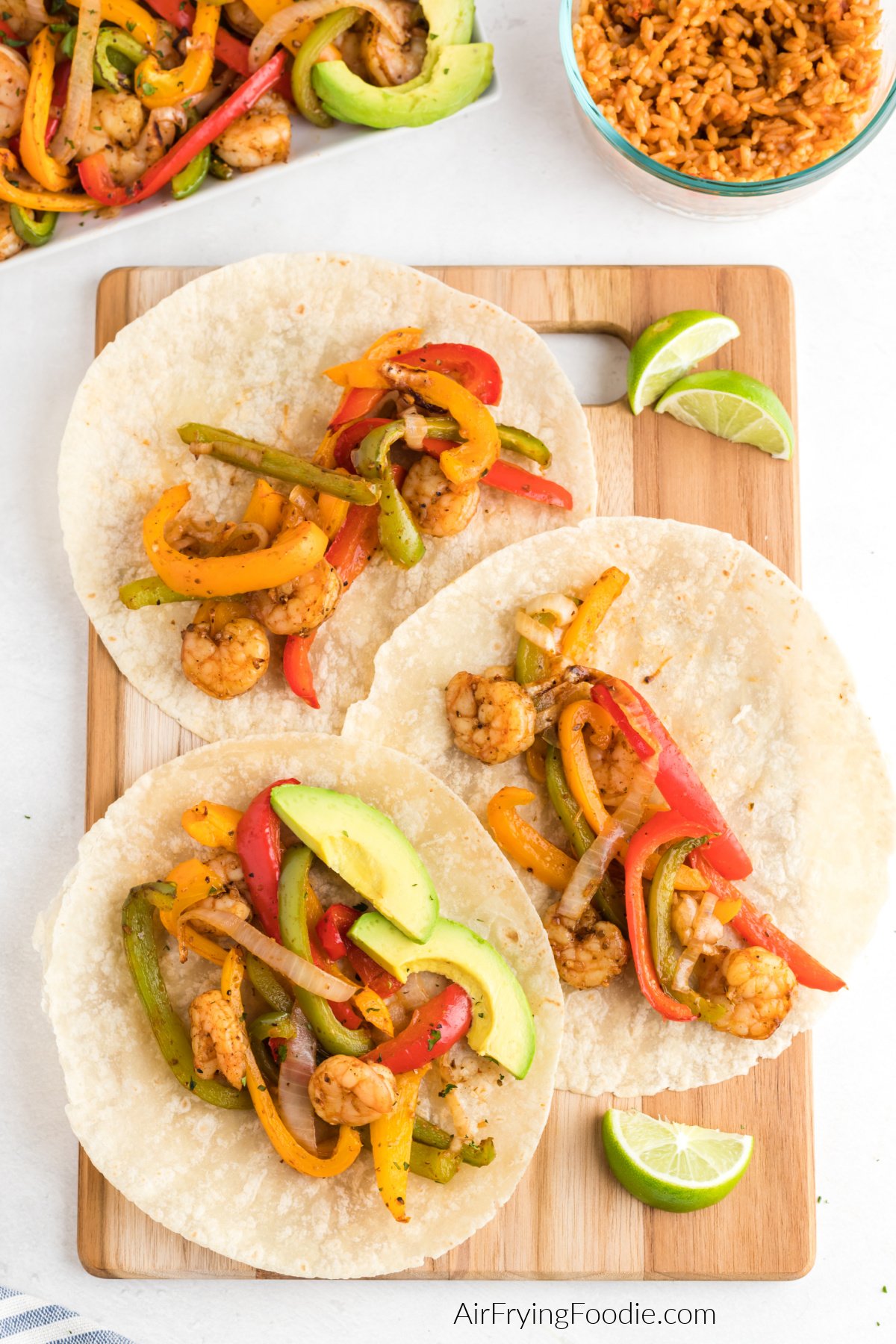 Air fryer shrimp fajitas served on tortillas with sliced avocado and a slice of lime. 