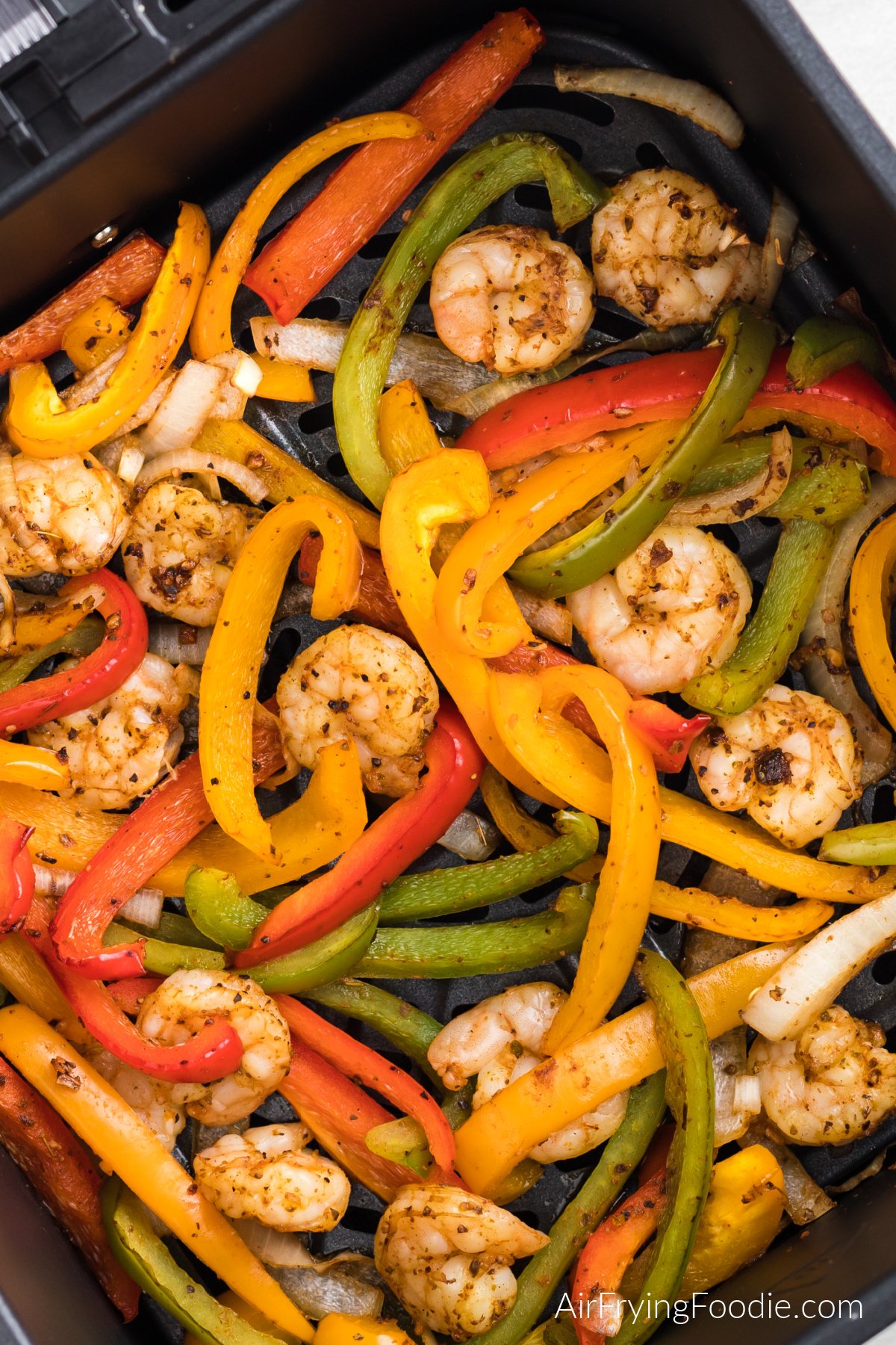 Shrimp, bell peppers, and onions, air fried for shrimp fajitas and in the air fryer basket.