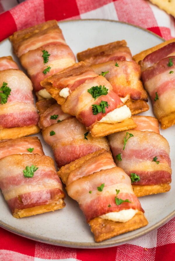 Bacon wrapped cream cheese crackers on a plate, ready to serve.