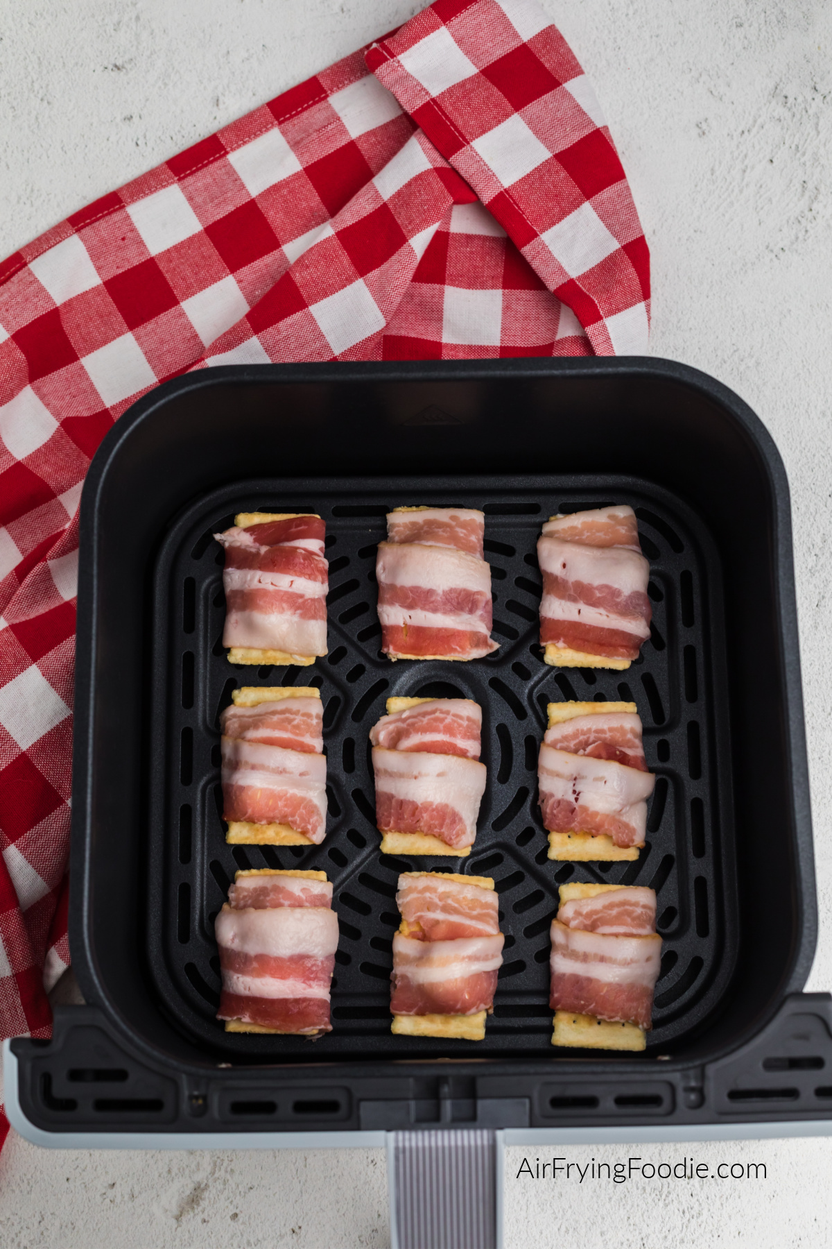 Bacon wrapped cream cheese crackers in the air fryer basket.