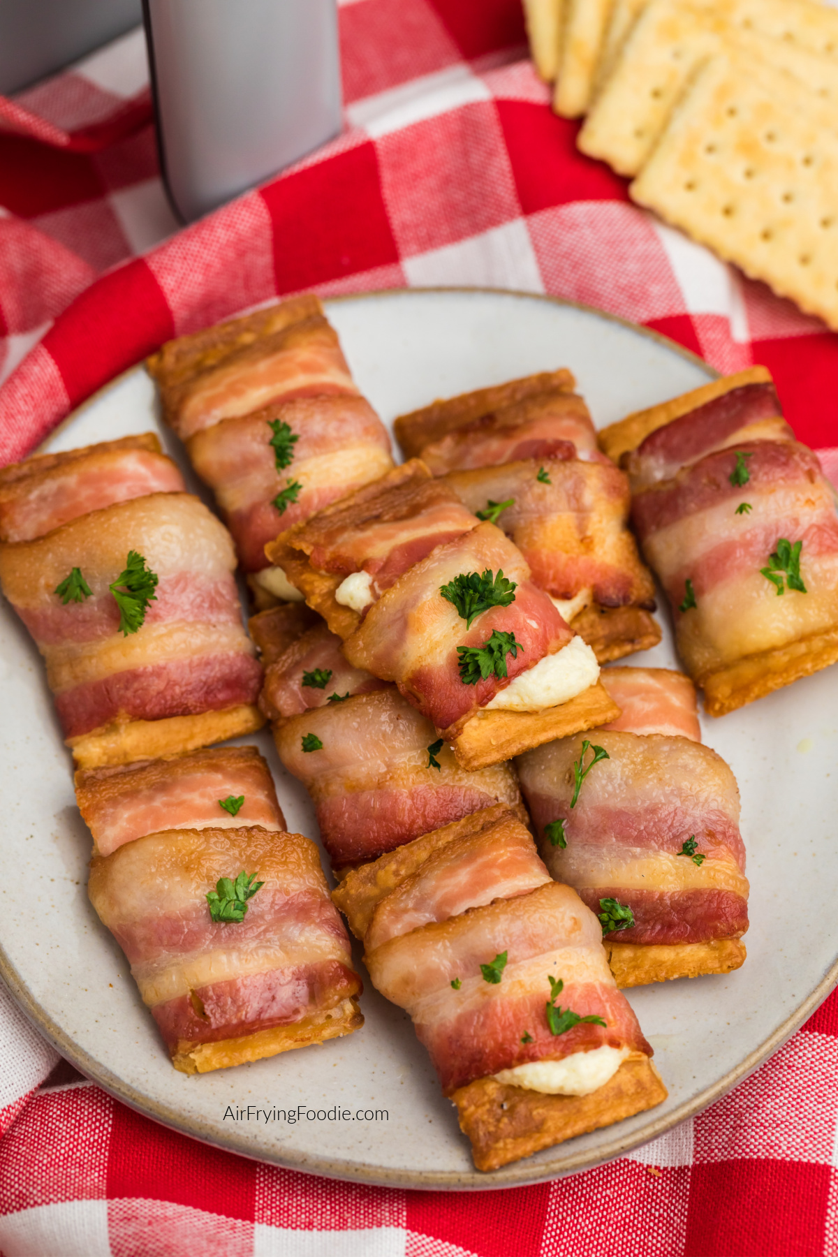 Bacon wrapped cream cheese crackers on a plate, ready to serve.