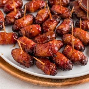 BBQ coated bacon wrapped smokies on a white plate