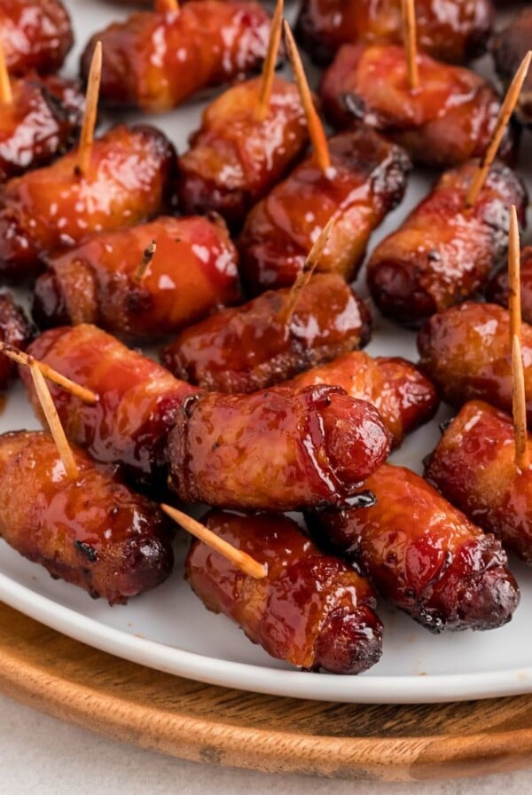 BBQ coated bacon wrapped smokies on a white plate