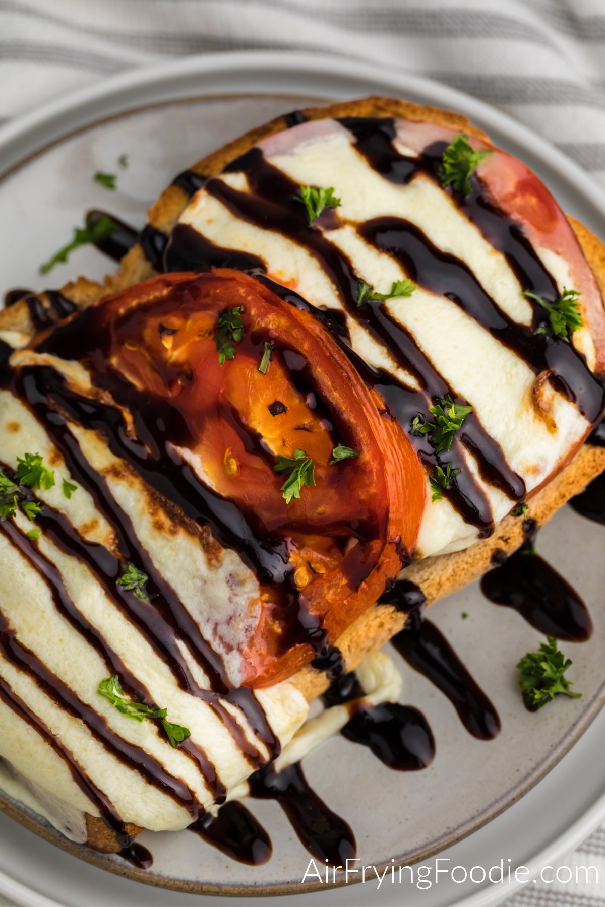 Balsamic glazed Caprese grilled cheese on a plate topped with fresh parsley.