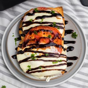 Caprese grilled cheese sandwich made in the air fryer and served on a plate with balsamic glaze.