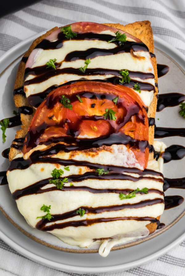 Caprese grilled cheese sandwich made in the air fryer and served on a plate with balsamic glaze.