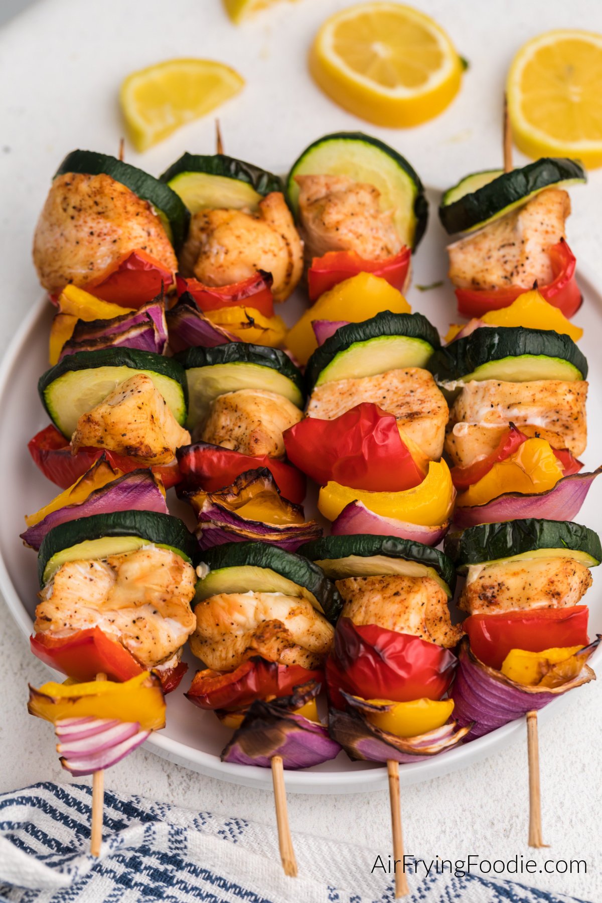 Chicken kabobs made with chicken breast and vegetables and served on a white plate.